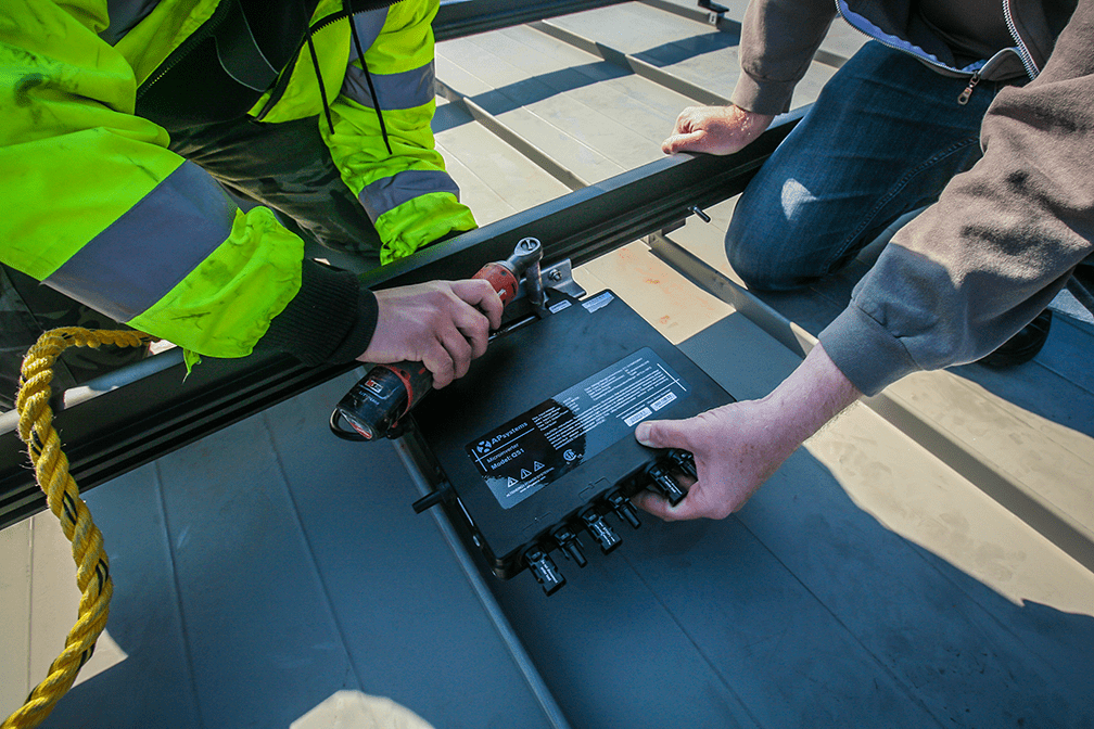 Serwisant montujący mikroinwerter APsystems QS1 na dachu
